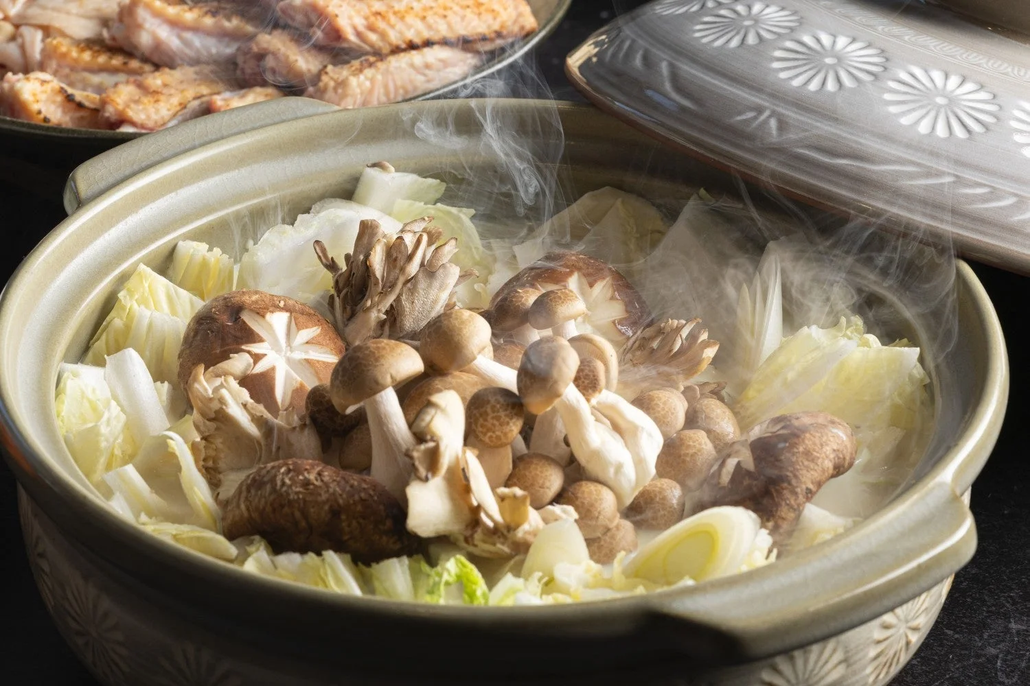 湯気が立ち上る土鍋に、きのこ類と白菜がたっぷり入った鍋料理